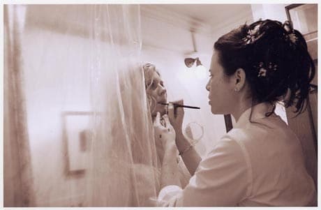Debra applying makeup to a bride in her veil