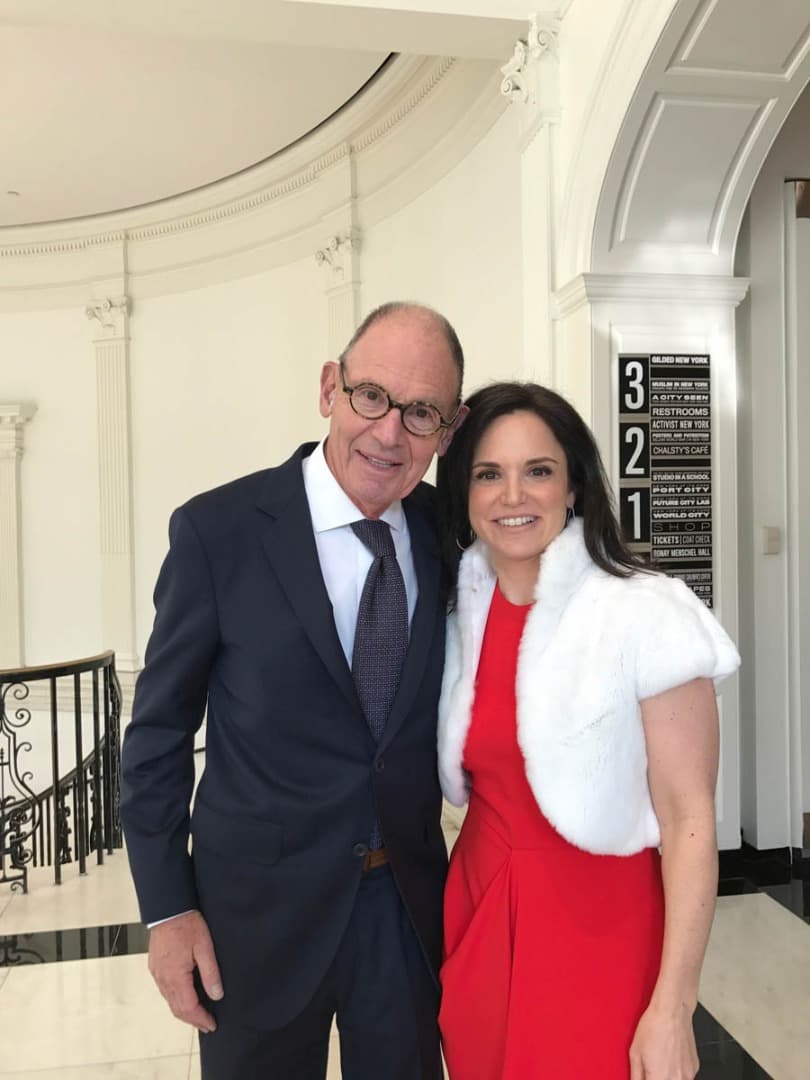 Man in glasses beside a woman in a red dress and white shrug