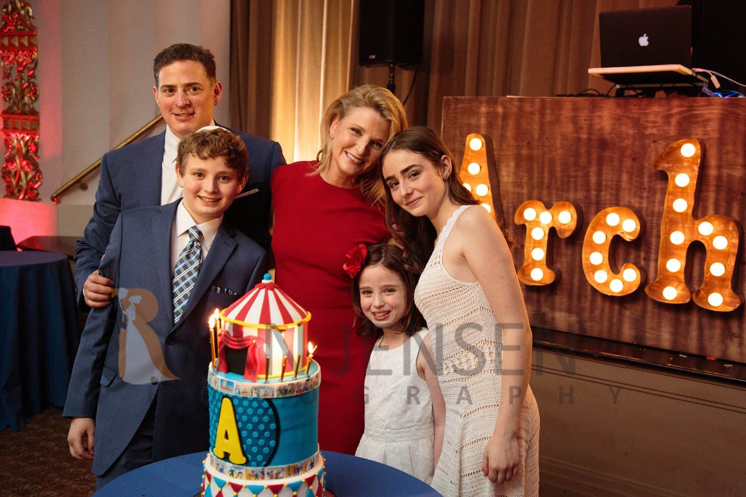 Family gathered around a circus-themed cake at a mitzvah party
