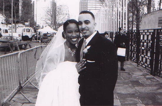 Black-and-white photo of a bride and groom on a city sidewalk